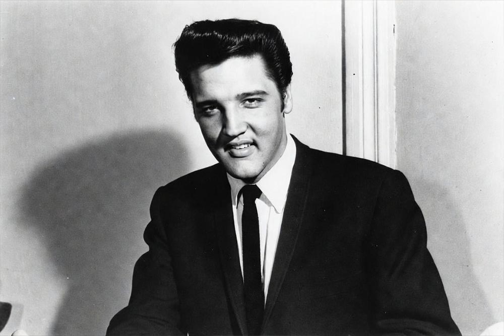 Elvis Presley w ciemnym garniturze i krawacie, czarno-białe zdjęcie portretowe